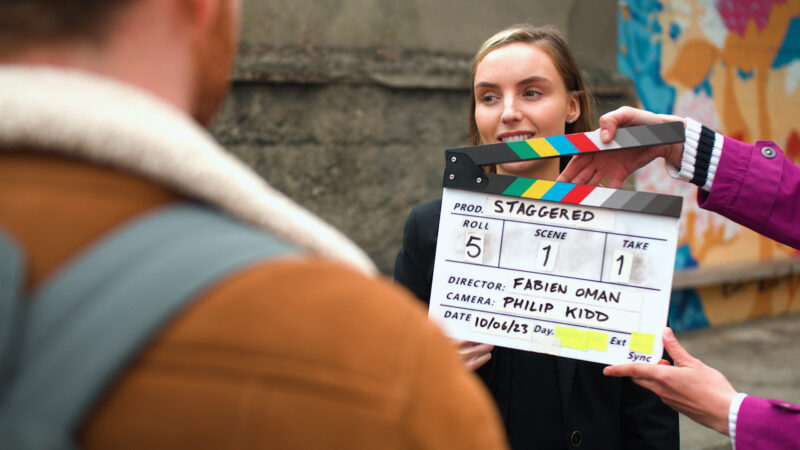 Blonde actress on a street behind a clapper board