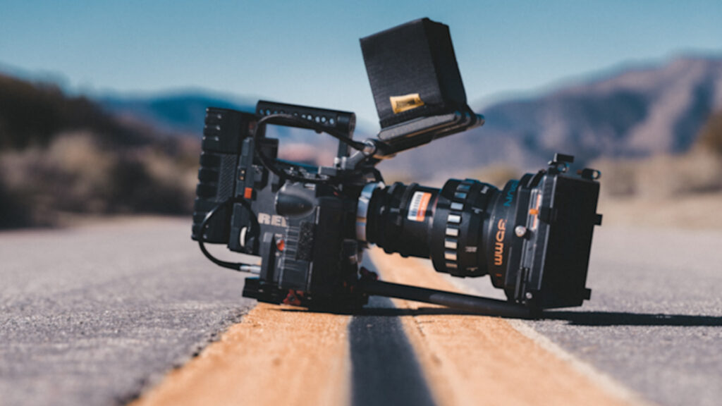 Red cinema camera on the ground with a large lens, external monitor and matte box