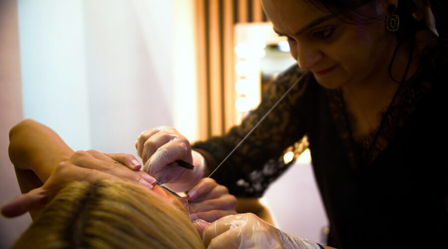 beauty technician threading woman's eyebrows