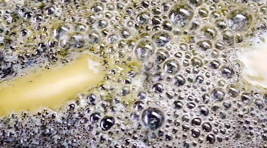 extreme close up of butter bubbling in a pan