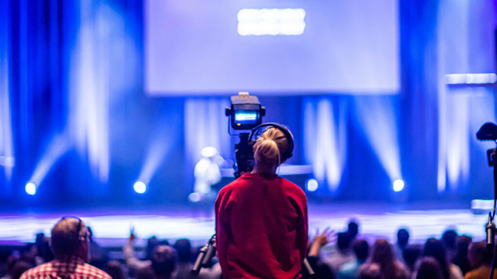 camera operator in front of a stage at a live conference event