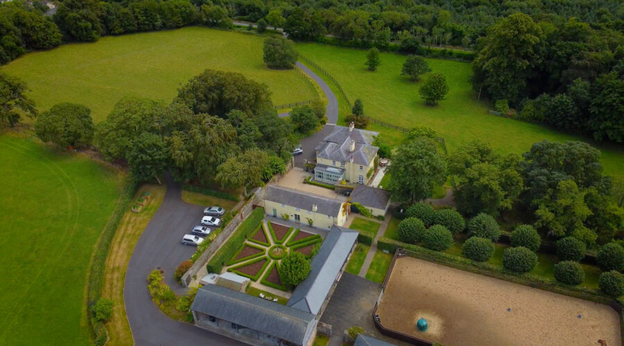 aerial drone shot of a farm house with a court yard and topiary garden