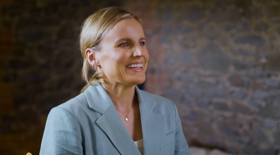 lady wearing a suit smiling and speaking to camera