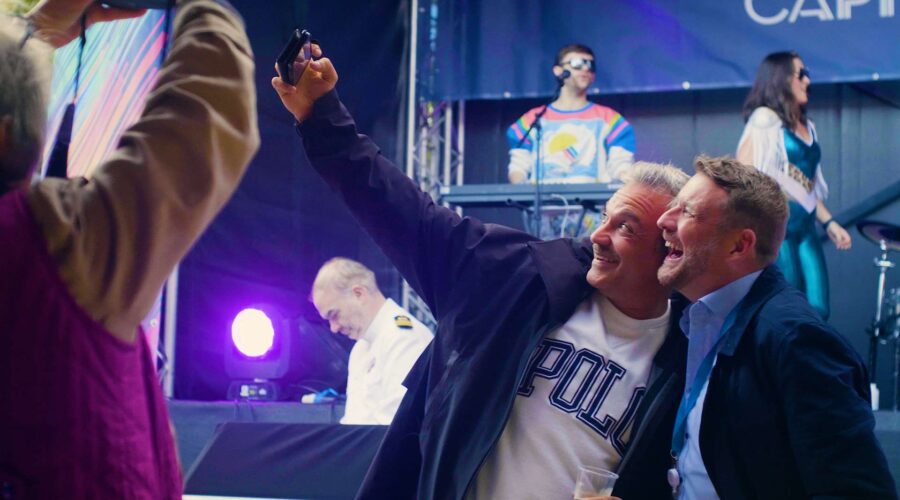 Two men taking a selfie at an outdoor concert event