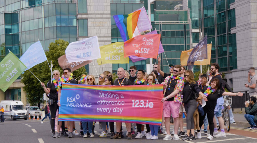 people waving branded flags on a Dublin street during the Pride Parade