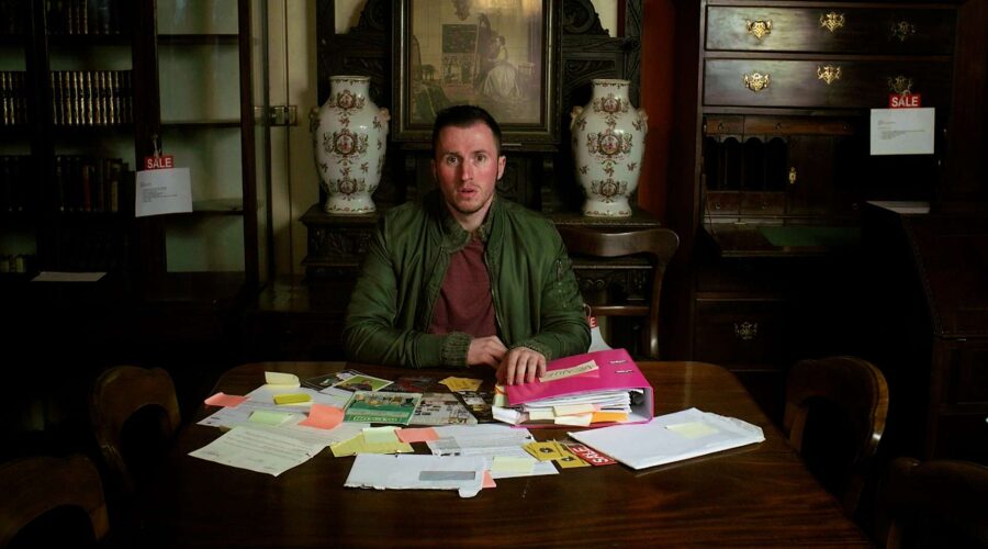 shocked looking man sitting in an antiques shot with lots of papers