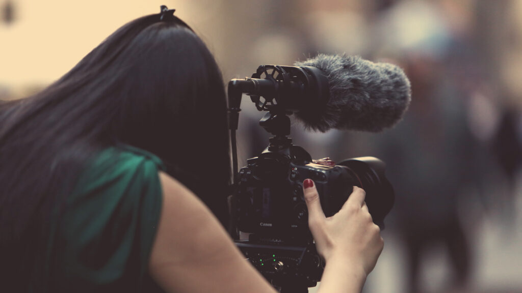 video camera operator with dslr camera and microphone in soft shallow focus