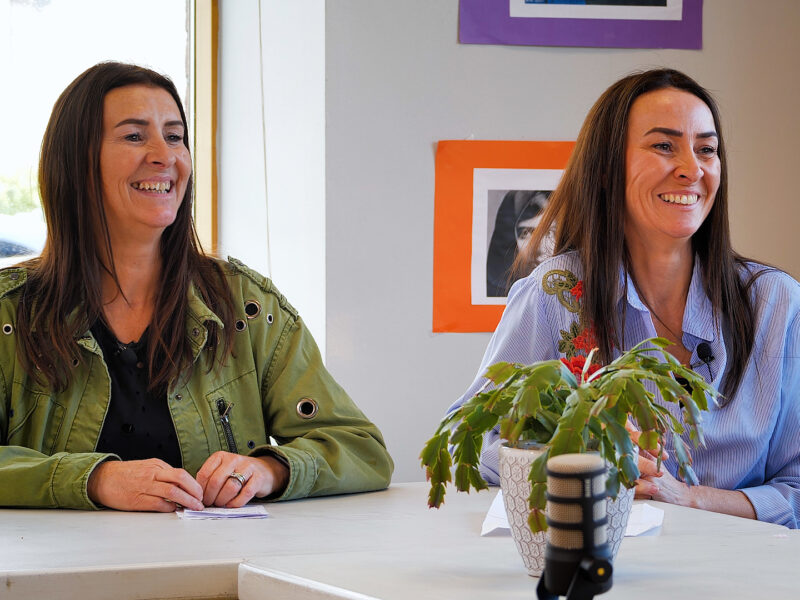 Two women smiling with podcast microphone